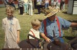 Man Dips Candles With Children on Festival Grounds. by Richard Hoffman