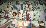 Woman Stands Among Racks of Quilts in Quilt Barn by Richard Hoffman