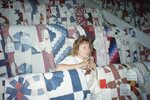 Woman Stands Between Rows of Quilts in Quilt Barn by Richard Hoffman